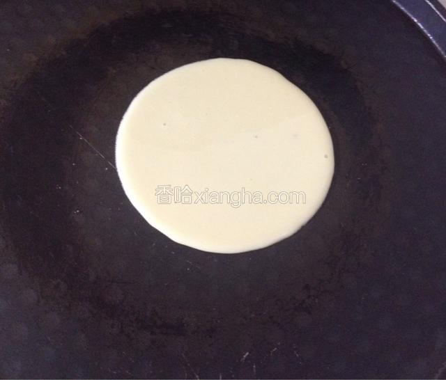 平底锅烧至七成热，用勺子舀一小勺慢慢往锅中央倒入面糊，让面糊自然均匀散开成圆形，（注意锅内不用放油）