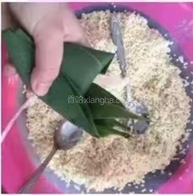 把糯米抖抖，结实点，
下面这一步比较难——
左手握住粽体，右手拿粽叶，再左手往右手扣，右手的粽叶盖住糯米，左手把两边的糯米向前捏，把两边的粽叶保住粽体，右手把剩余的粽叶往边上按，往粽子上捆竹条就行（捆绑的方法有很多种）