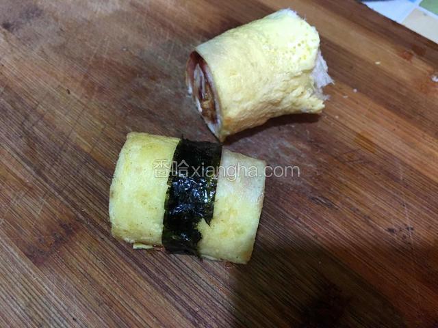 卷好后将两头切平整，从中间切开，取一片海苔如图卷起，用少许草莓酱粘连