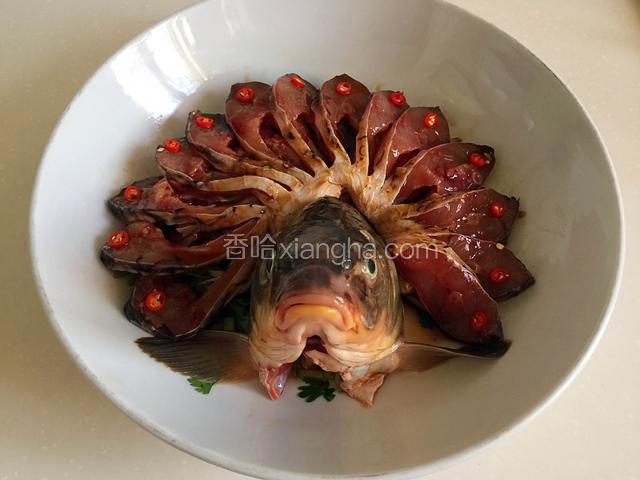 如图所示摆放好鱼肉，剖开的鱼尾垫在下面，放些辣椒圈。