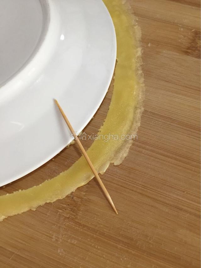 取盘子一个倒扣在面皮上用牙签划去多余面皮使面皮成均匀的圆形