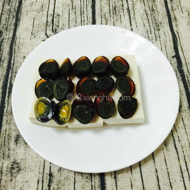 把豆腐切对半切开，切小块，铺在盘子上。把切半的鹌鹑蛋铺在上面，淋上伴好的蒜蓉酱。
