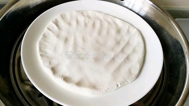 盘里放入糯米粉团，用手掌摁成饼状。上锅蒸20分钟。