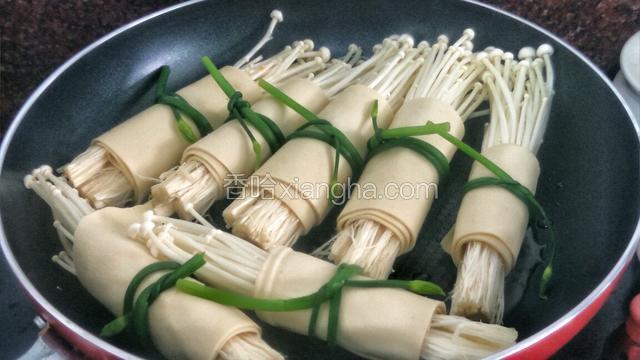 油热后就调小火把金针菇豆皮卷整齐放入