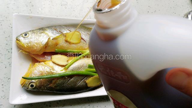 鱼肚子和鱼表面都放上葱姜。倒入适量料酒腌制半小时。