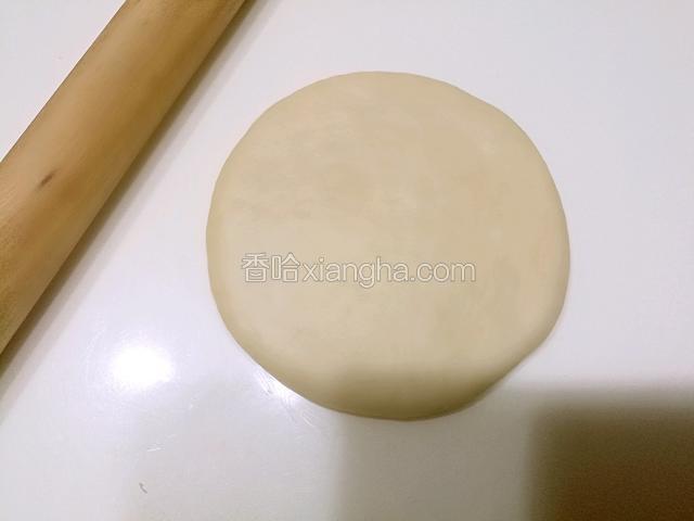 把包好的椰蓉馅收口向下，用擀面杖擀成薄薄圆形。