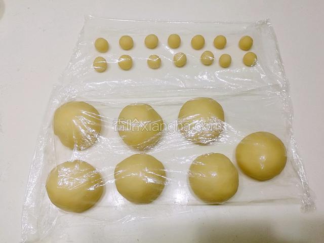 取出放在台面上揉一揉排气，排气后把大面团分成7个，每个50克，小面团分成14个，每个4克，揉成圆盖上保鲜膜静置10分钟。