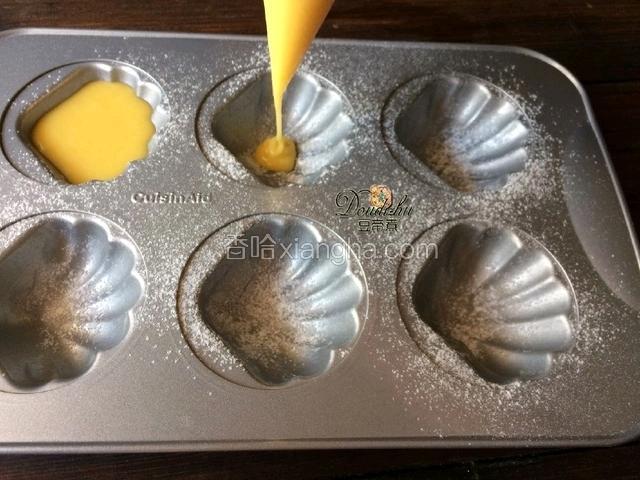 在放置的时间到后把蛋糕糊倒入裱花袋，剪个小口挤压入模具。八分满即可