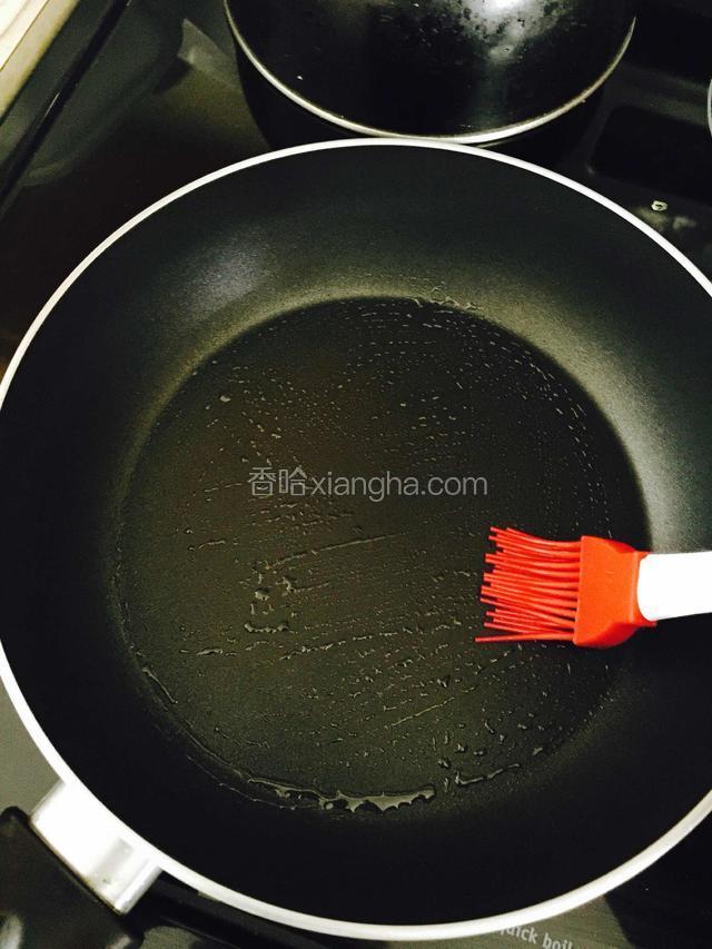 找一个平底锅，开小火预热。准备适量的食用油和一个小刷子，在锅底涂一层油