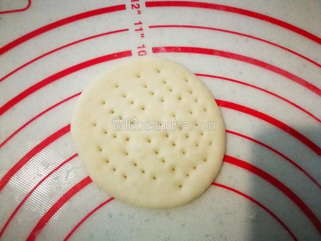 把小面团擀成饼状，用叉子在上面扎孔。