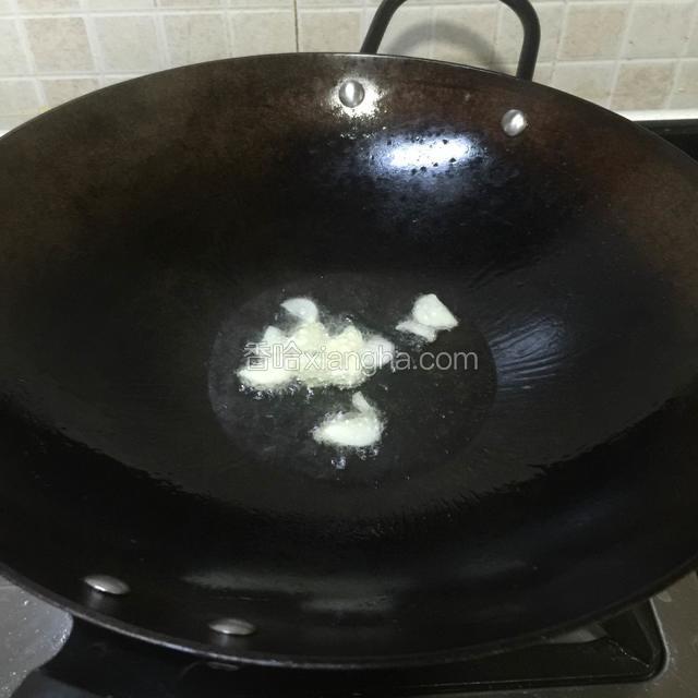 烧热炒锅，倒进适量山茶油，再倒进蒜瓣片，中小火爆香。

