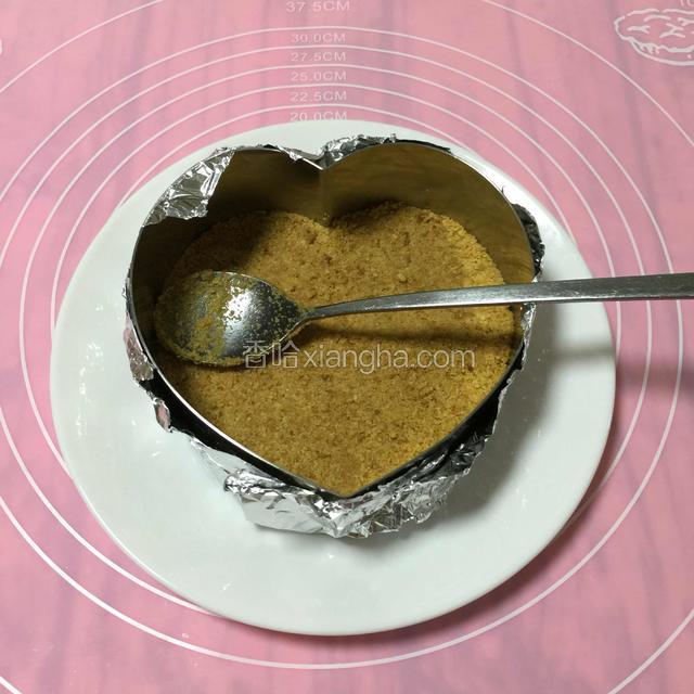 锡纸垫底包住模具。
把搅拌好的饼干碎加进模具里面，
用铁勺子用力~压实压平。
PS：锡纸包不包其实关系不大，因为是整个盘子一起放进冰箱。