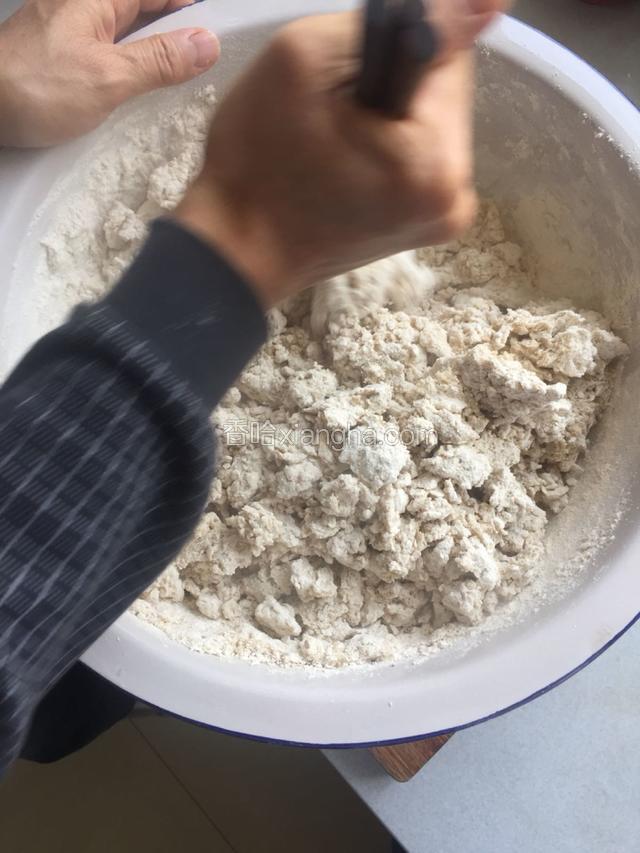 烧一壶开水倒在莜面预留的剩下一半的空间。水面和莜面高度相同。用三根筷子握住搅匀。