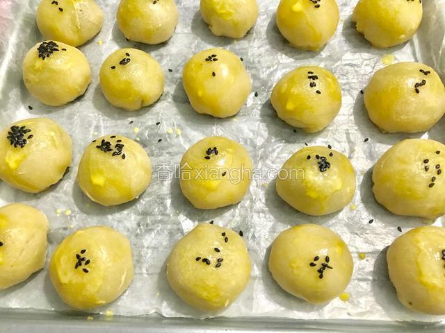 从烤箱里拿出烤了5分钟后的酥饼，刷上蛋黄液，马上撒上黑芝麻（要趁蛋黄液没干的时候撒上黑芝麻，干了黑芝麻就粘不住了）