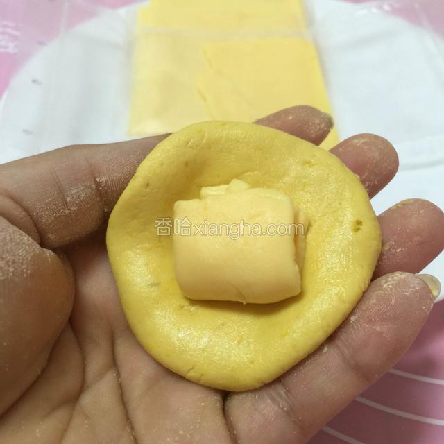 搓成圆团。用手腕轻轻压平，撕开一片芝士，撕一半，做馅。
本菜谱是一张芝士做二个馅，刚刚好，满满的芝士酱。