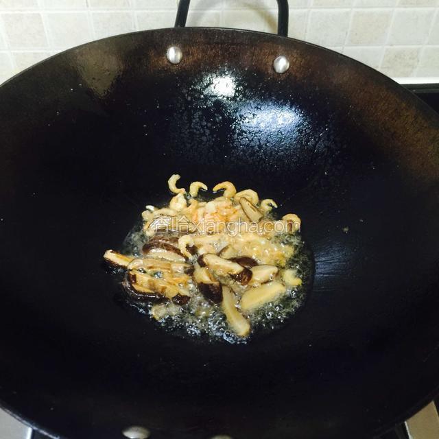 开中火，热锅，倒进适量熟猪油，
把虾米和香菇片倒进锅里拉拉油。
拉一下油才能把二者的香味逼出，
用来炒韭菜花更香。
PS：这道菜，用熟猪油炒更香口。