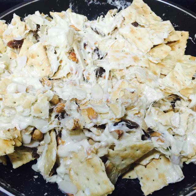 小心翻伴，让糖粘住果仁和饼干，
可以看出牛扎糖有些许拉丝了。