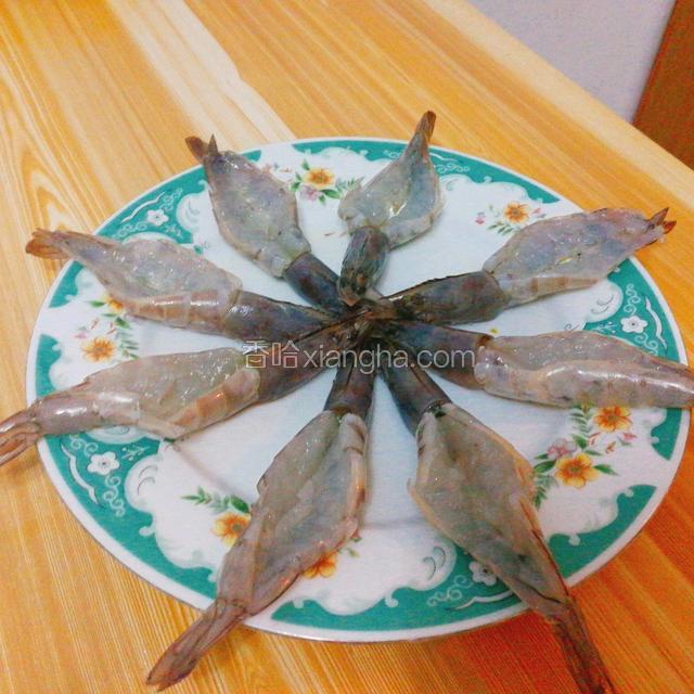 解冻好的虾剪去须、脚；剪刀在虾背剪开壳，去除沙线；用刀将虾肉分成两半。为了焗虾时防止收缩变形，可以在虾肉上横断划两刀（进入烤箱加热时不容易变形弯曲）每个开背后的虾上面滴两滴料酒腌制十分钟入味备用