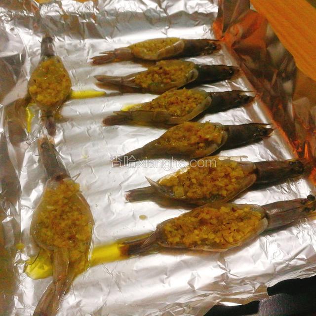 烤盘内放入铝箔，把腌制好的虾摆放整齐，中间留点让芝士喘息的空间，用小勺给每个虾背上放上我们炒好的调味汁（蒜蓉），这时候烤箱180℃预热五分钟