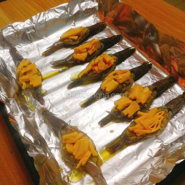 这就是关键的一步了，把切碎的芝士碎整齐的放在虾背上（也就是放在蒜蓉上，一定放整齐不能在烤制过程中掉下来，那样的话这道料理就不美观了哦）现在把烤盘放入烤箱，200℃烤15分钟出炉即可