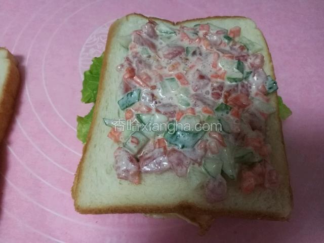 搭上一片生菜,盖一片面包,放入拌了沙拉酱的杂蔬,再盖上面包片
