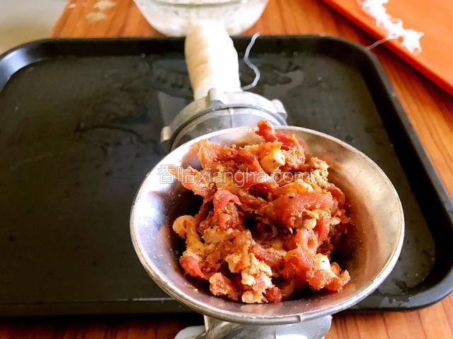 再将腌制好的肉丝放入灌肠机的入口的漏斗里