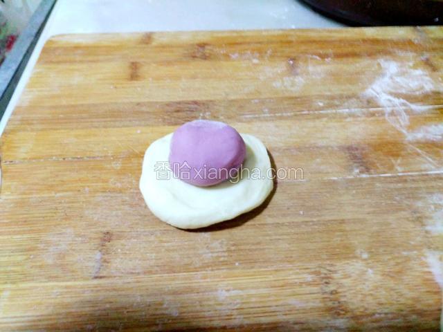 把白面团分成大小均匀剂子，按成饼，放上紫薯剂子
