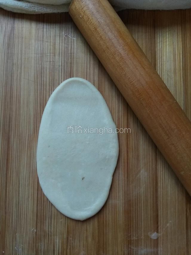 取一个包好油酥的面团，用手按扁，再用擀面杖擀成长舌状如图