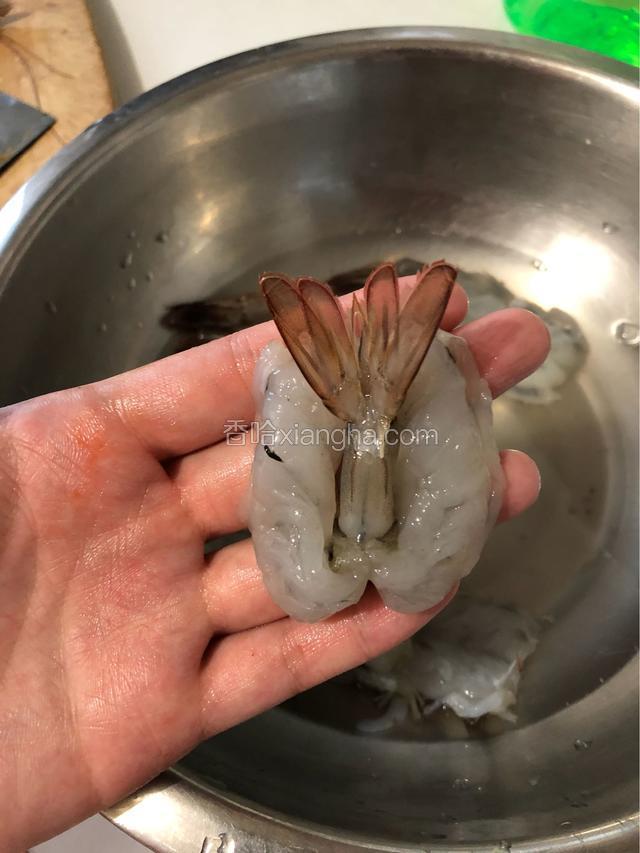 把虾尾从中间的空隙中翻出来。倒料酒，去腥。