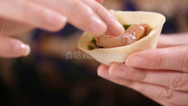 填入馅料，再包入一直鲜虾仁，捏实另一边呈三角状；