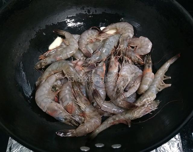 锅内倒油烧七八分热，放入虾用筷子翻炒至两面变色。