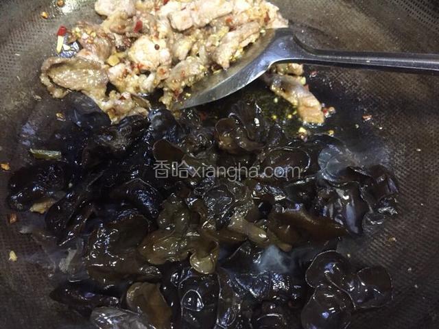 把肉片推至一边，倒入黑木耳，让黑木耳充分吸足油料
