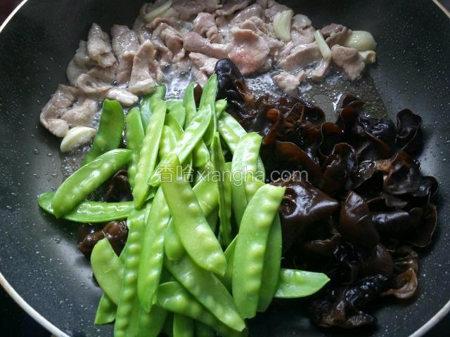肉片推向一边，放入焯好水的荷兰豆和木耳。