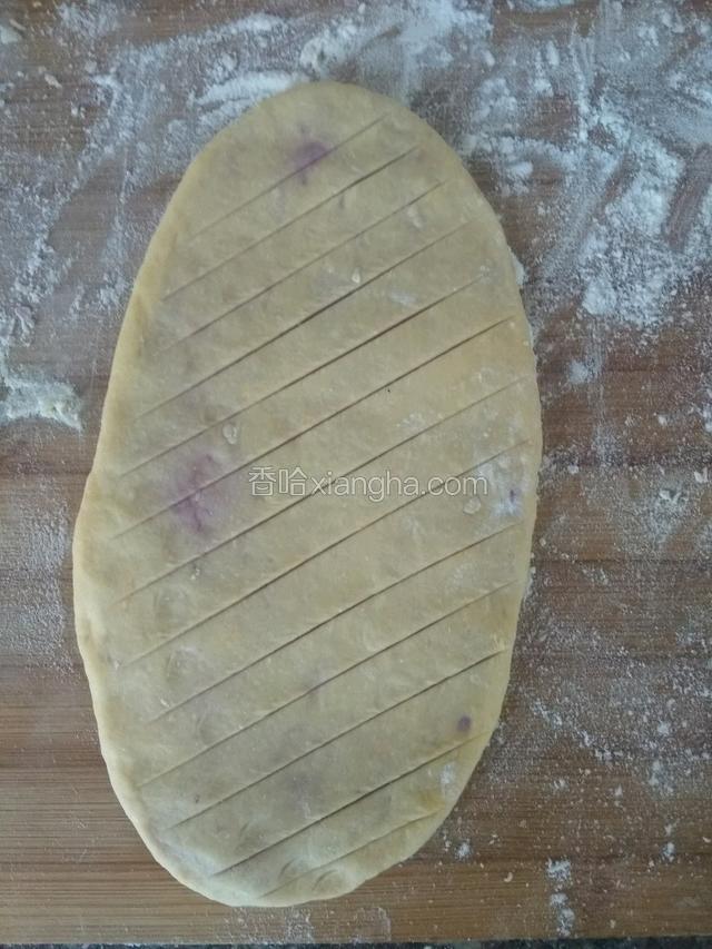用擀面杖擀成长舌状，用锋利的刀子在面皮上面画斜刀口，注意不要切到底部！切到紫薯面团即可！