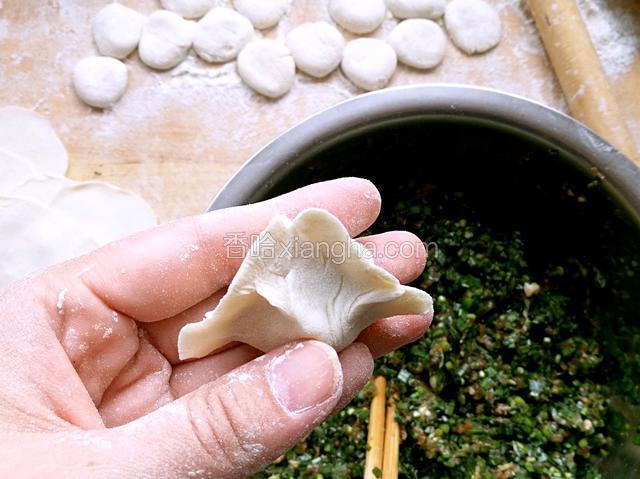 双手中指托底，拇指与食指同时往中间挤，一个饺子就包好了