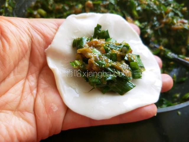 取一张饺子皮，在饺子皮的边缘抹上清水，放适量的肉馅。
