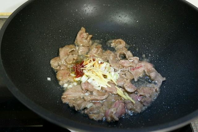 在加入姜丝、葱花、郫县豆瓣酱炒出香味