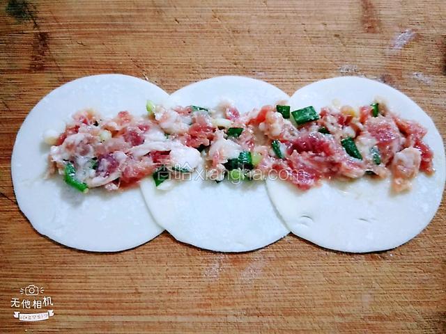 在饺子皮上半部铺少量肉馅