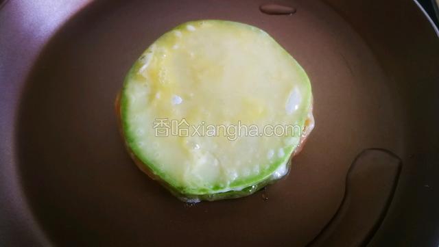 沾上蛋液包住整个食材。
坐锅点小火，不粘锅放少量植物油，放入瓜片，煎一分钟翻面。