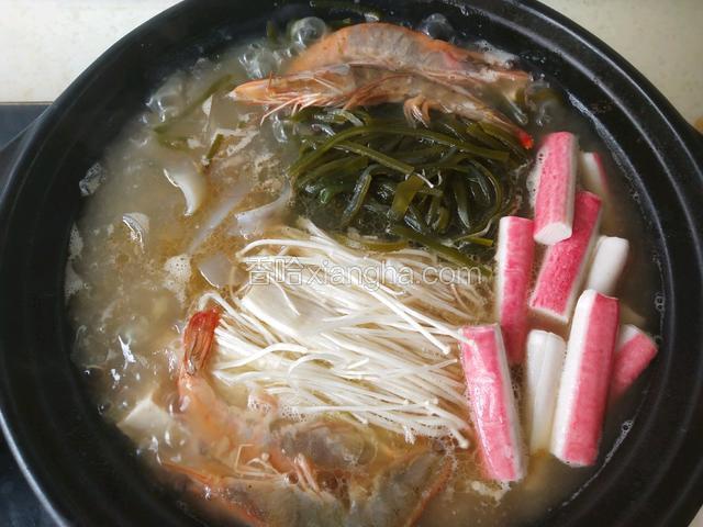 待牛骨汤烧开，加入前面准备好的配菜，先放入北豆腐，中小火煮制15分钟，(提前放豆腐的目的，是为了让豆腐更入味)。在加入金针菇，大虾，宽粉，海带，待汤开后转中小火煮5分钟断生。(因为牛骨汤已经加过盐了，所以沙锅汤里就无须在加盐了)。