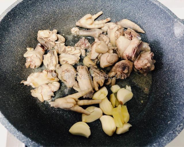 水份炒干，鸡油被炒出。
这个时候加入切好的生姜片和蒜瓣继续翻炒2分钟，可以闻到蒜香味。