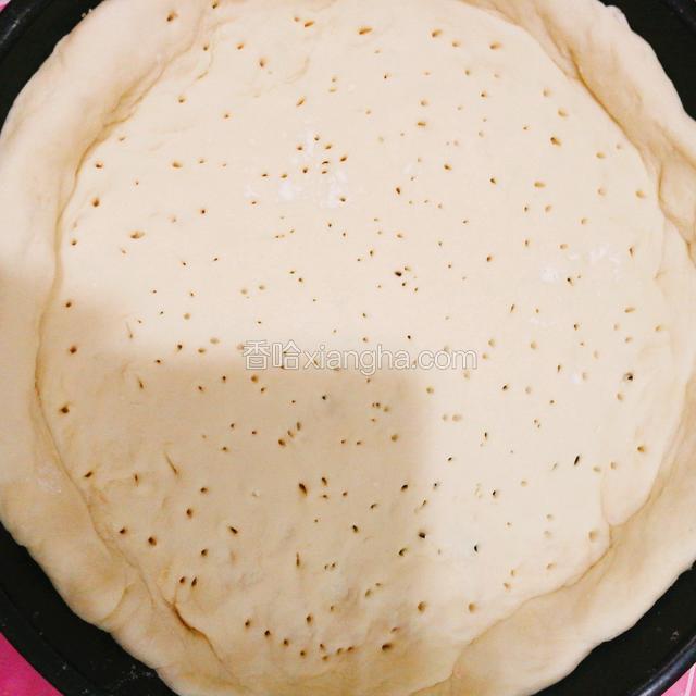 面粉发酵完后，在按板上用擀面杖擀成圆饼，边缘厚一点点，披萨盘刷一层油，把披萨底放好，用牙签扎出很多小孔