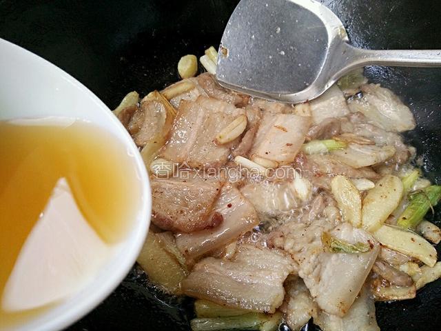 如图见五花肉片两面微黄这时就烹入料酒翻炒均匀
