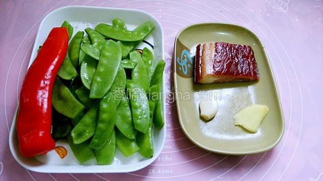 荷兰豆摘去筋洗净。大红椒一个去籽洗净。腊肉一块洗净。姜一片、蒜头一瓣洗净。