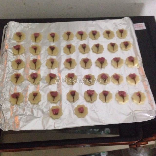 樱花挤干水分放在饼干中间，再用手压一下。