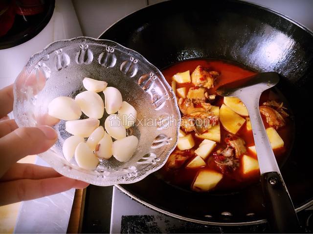 待锅中水煮沸时，倒入准备好的土豆块和大蒜子，并放入盐和胡椒粉，调制大火档位烹煮