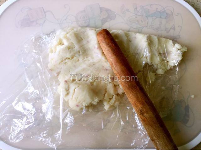 山药蒸熟后稍微摊凉一下，用保鲜膜包好放在砧板上，用擀面杖捶打、碾压成泥状。