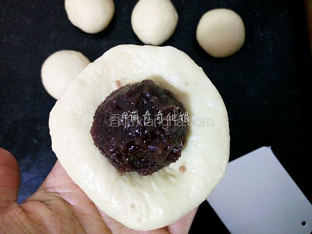 松弛好的面团光滑面朝下压扁，放入一个豆沙。