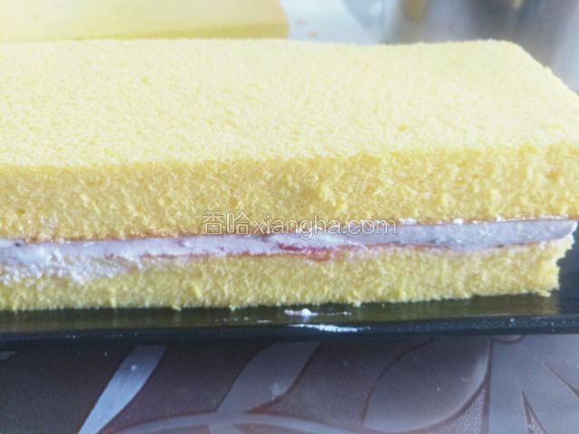 取一片蛋糕片，在上面抹上奶油，再放上一片蛋糕片，再抹奶油，再放蛋糕片