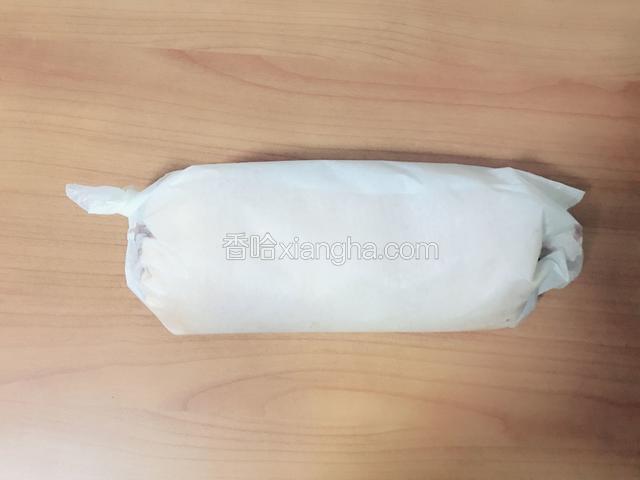 借助擀面杖将蛋糕卷起来，然后用油纸包住，放冰箱冷藏半小时左右